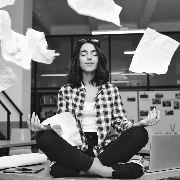 girl sitting on desk with paper swirling around her